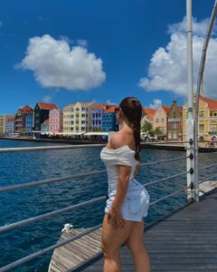 Vrouw kijkt uit over de Pontjesbrug en de kleurrijke Handelskade in Willemstad, Curaçao