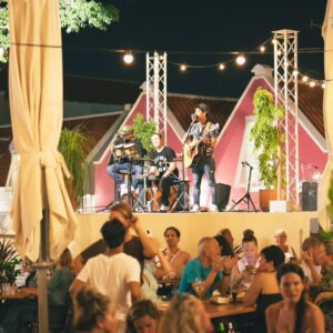 Band speelt live muziek op een sfeervol podium tijdens Night at the Village Curaçao, met bezoekers die genieten op het terras van Kurá Hulanda Village