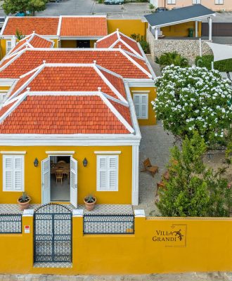 Voorzijde van 5 sterren villa Curaçao – charmante stadsvilla met rood dak, gele gevel en privé-ingang in Willemstad
